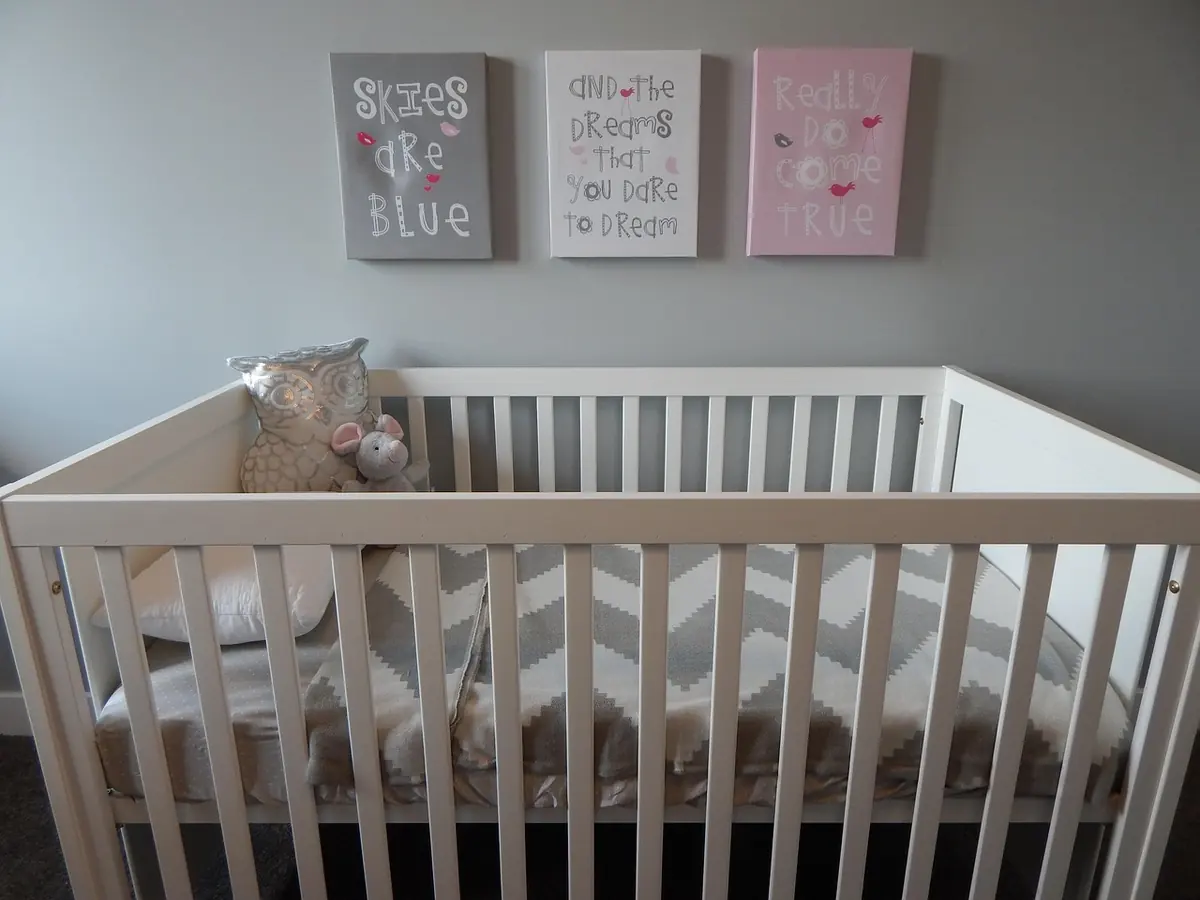 White crib in a nursery with three framed prints on the wall